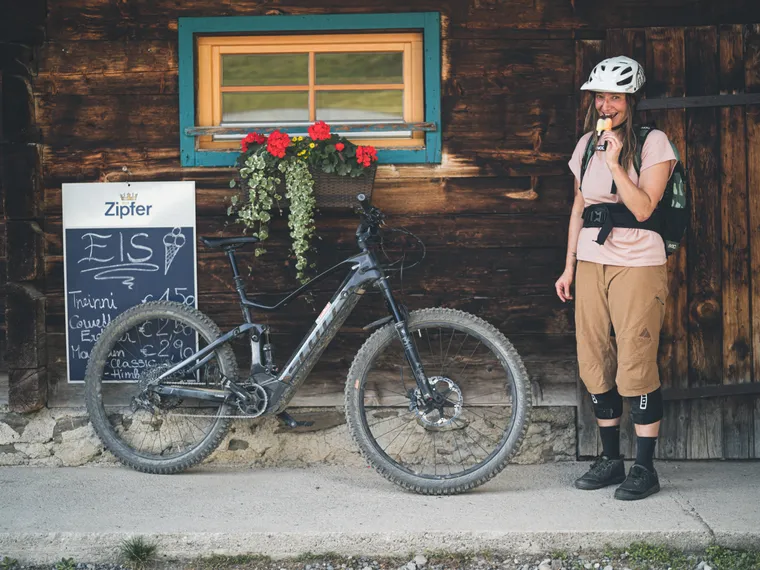 Bikerin mit einem Eis vor einer Almhütte in Saalbach
