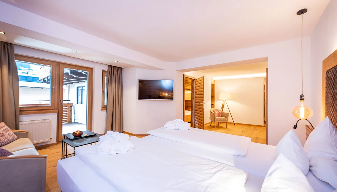 Helles Hotelzimmer mit Doppelbett, Holzboden, moderner Einrichtung und Sitzecke