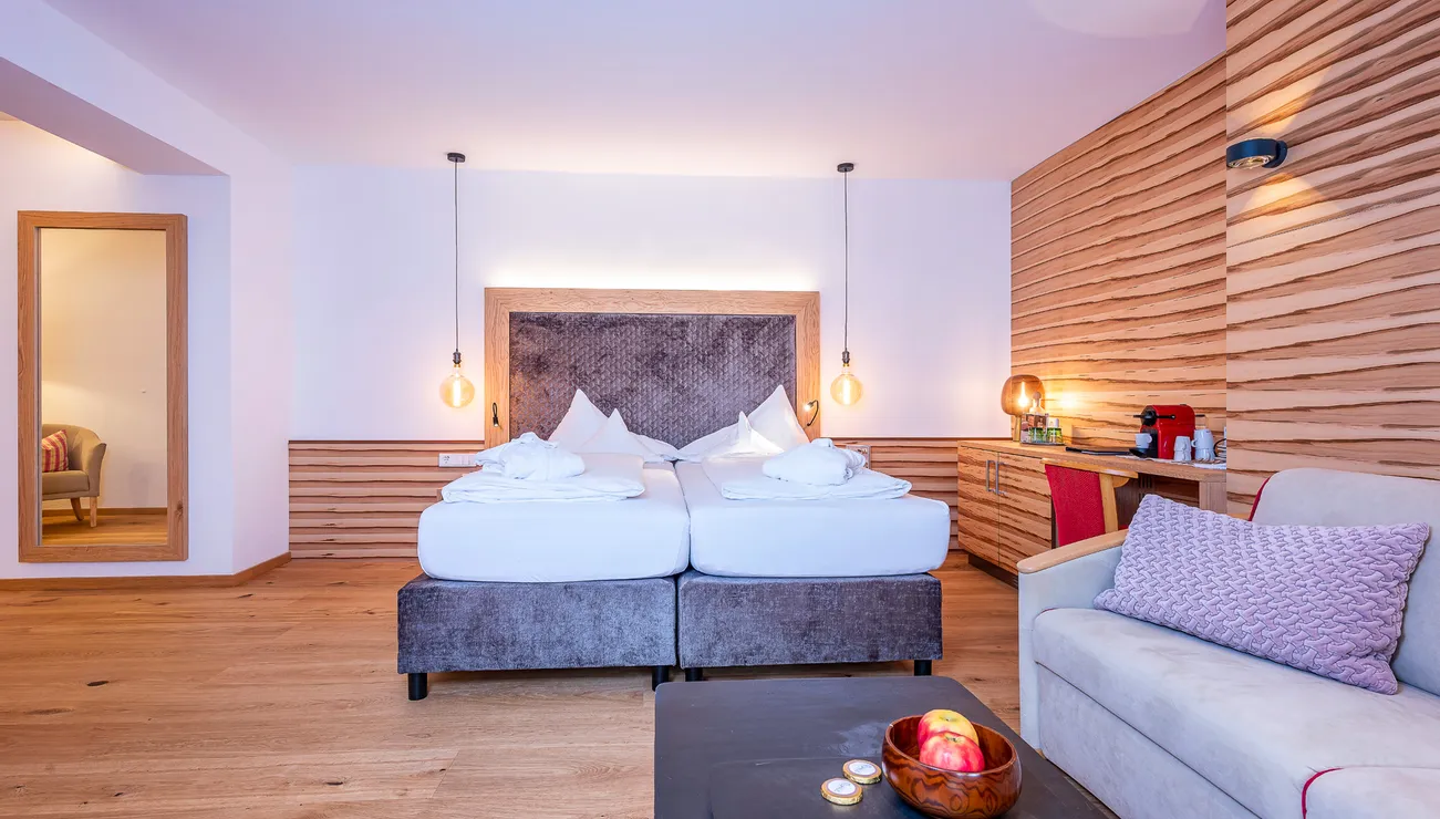 Modern hotel room with double bed, wood paneling and cozy seating area