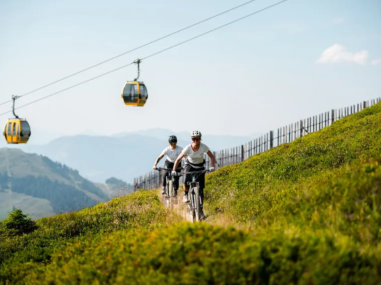Mountainbiker am Berg mit Gondel im Hintergrund
